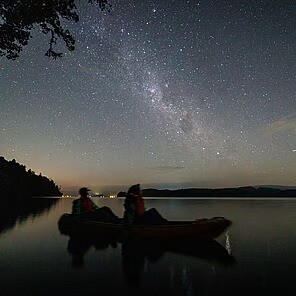 Two kayakers on the lake observing the Milky Way